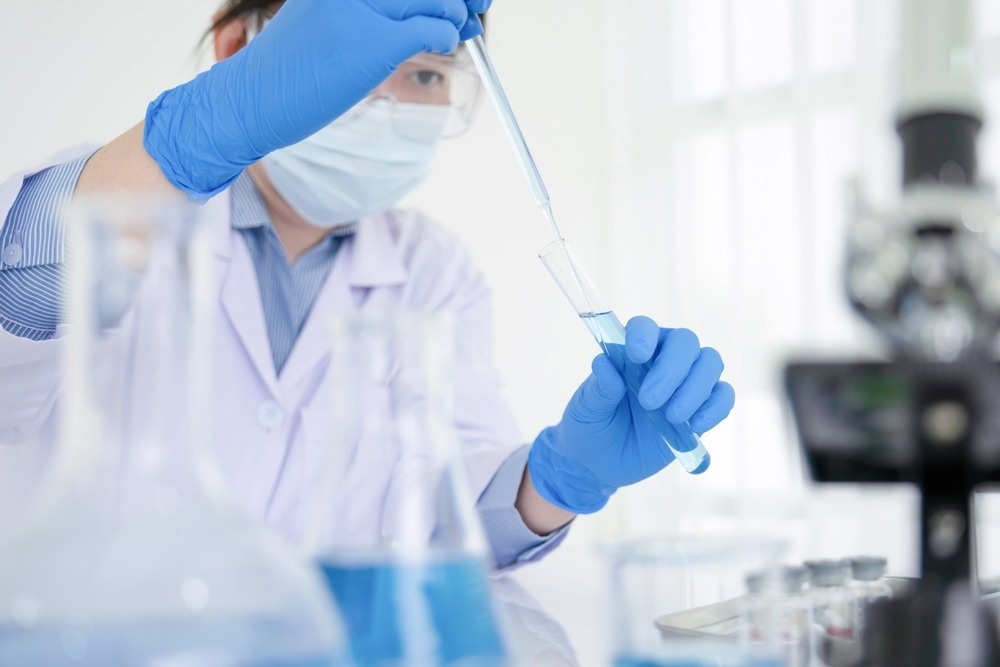 Young female scientist or researcher dons protective attire and conducts experiments in the laboratory and tests new substances and carries out crucial research for development purposes.