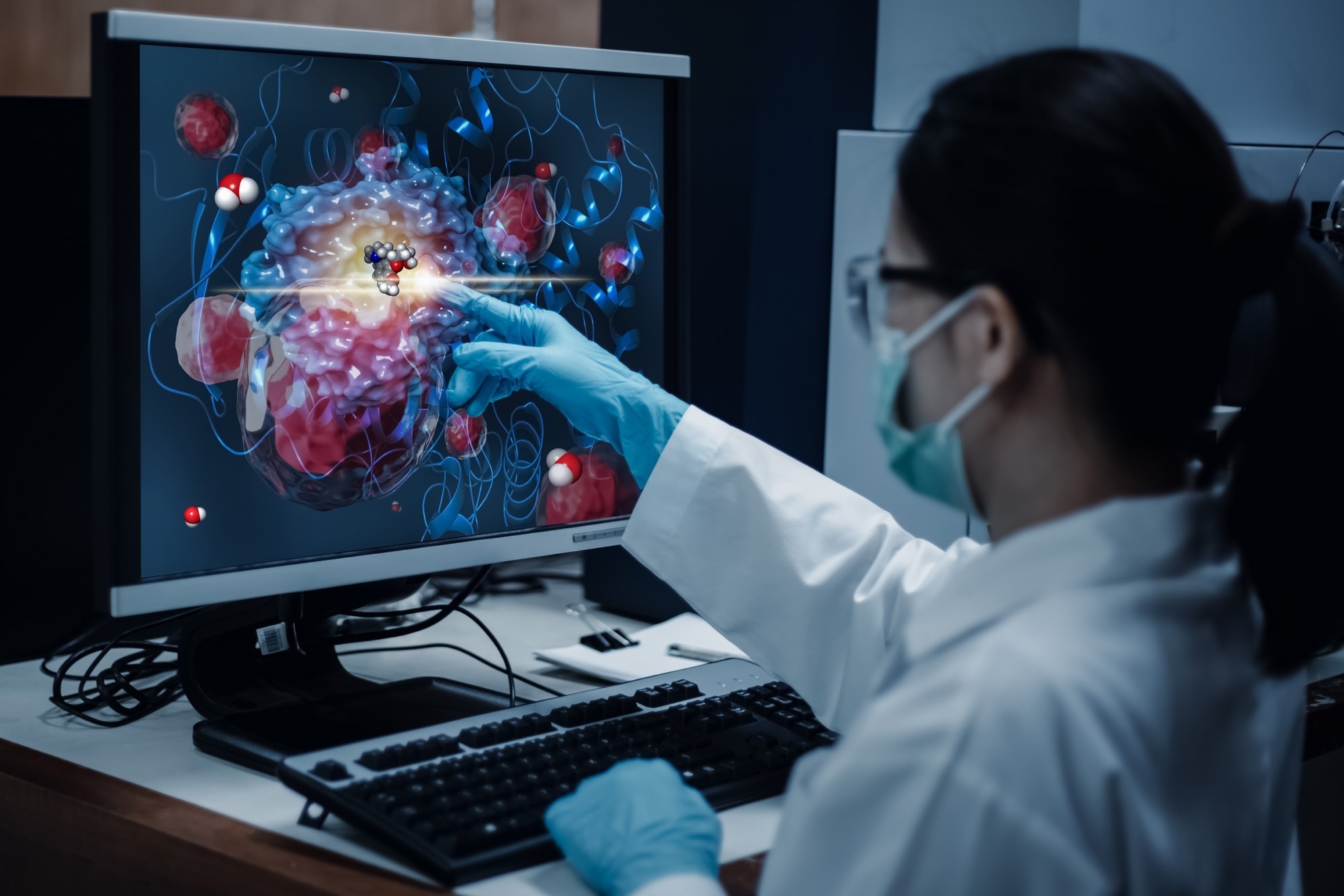 Researcher woman indicates the position of drug sample in the modelling simulation of drug development as shown on a computer monitor.