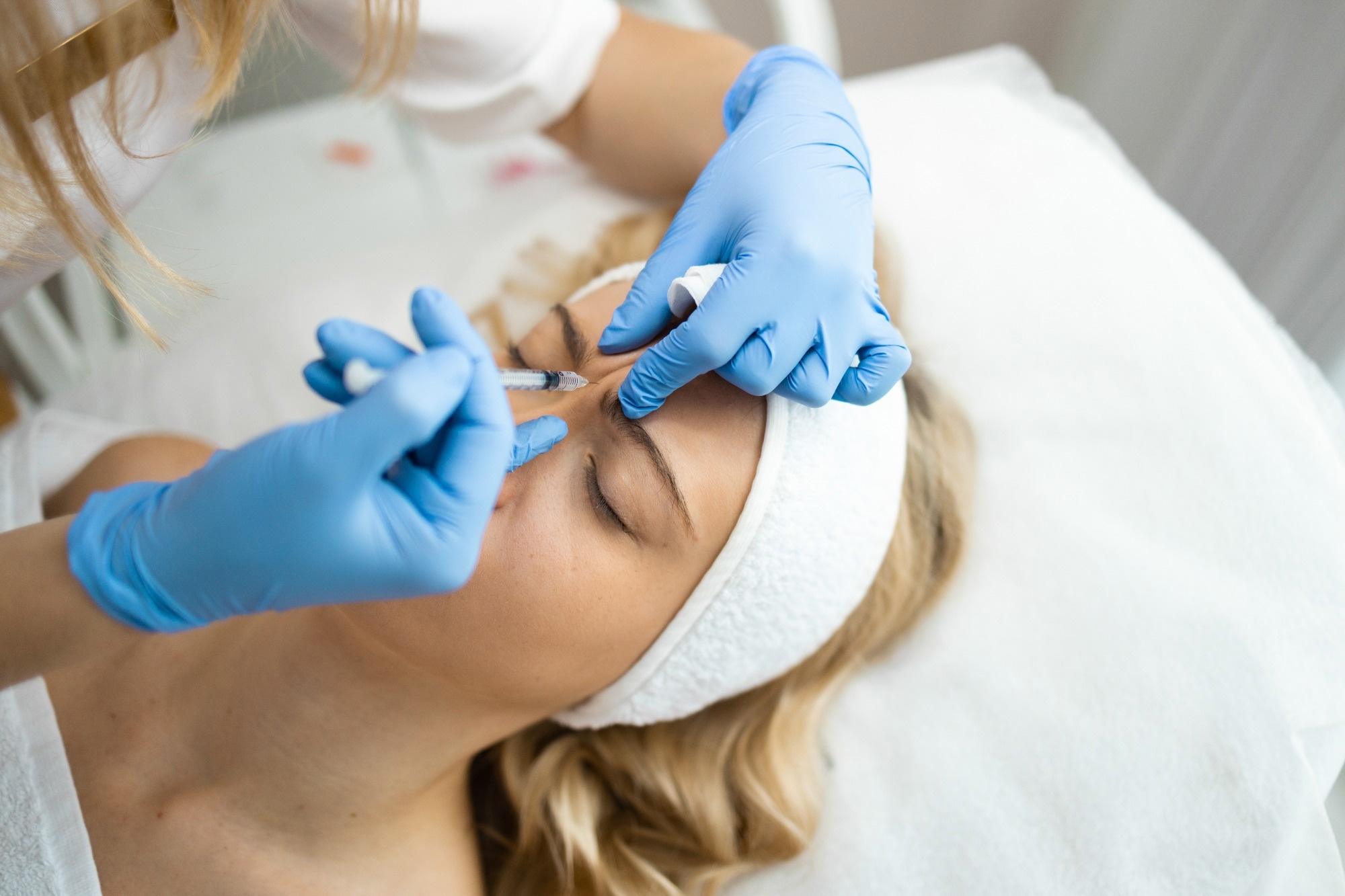 Cosmetologist makes rejuvenating anti wrinkle injections on the face of a woman