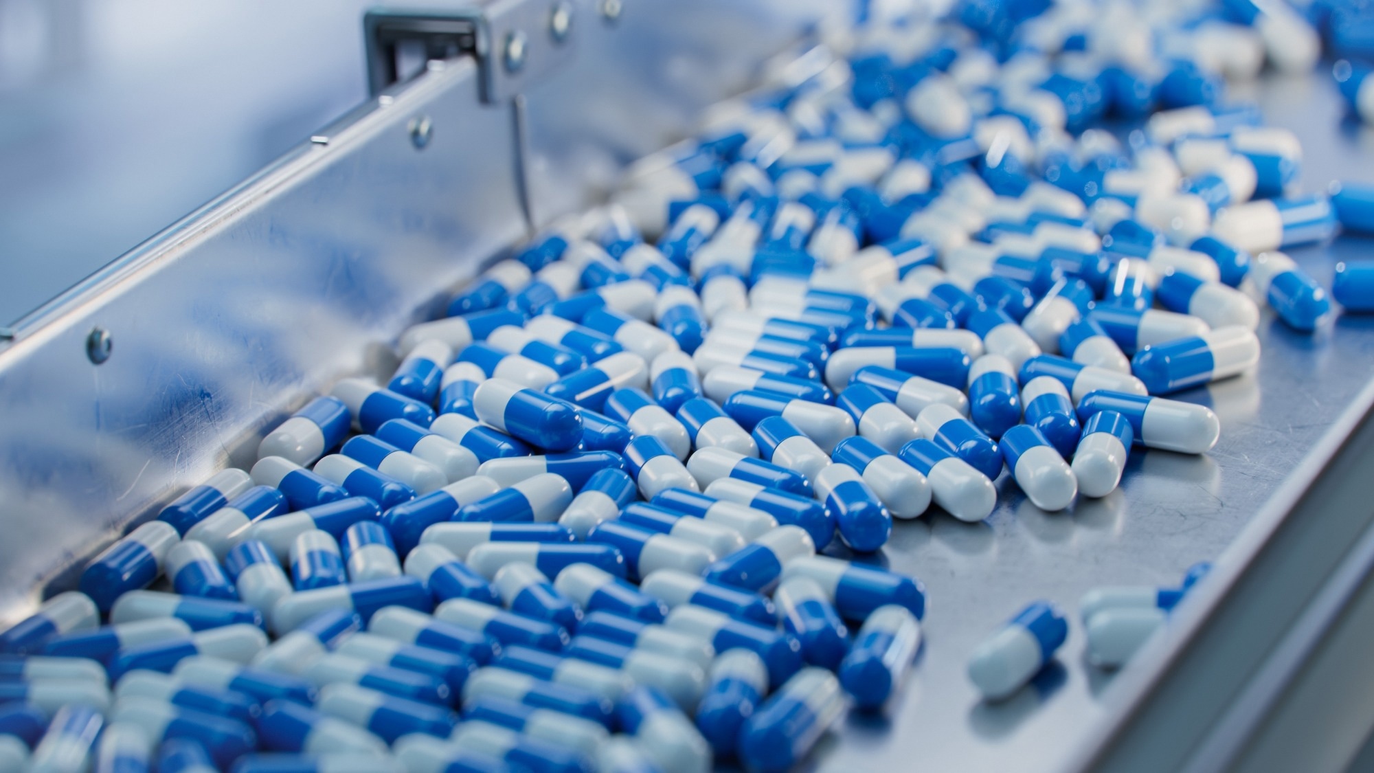 Blue Capsules are Moving on Conveyor at Modern Pharmaceutical Factory.