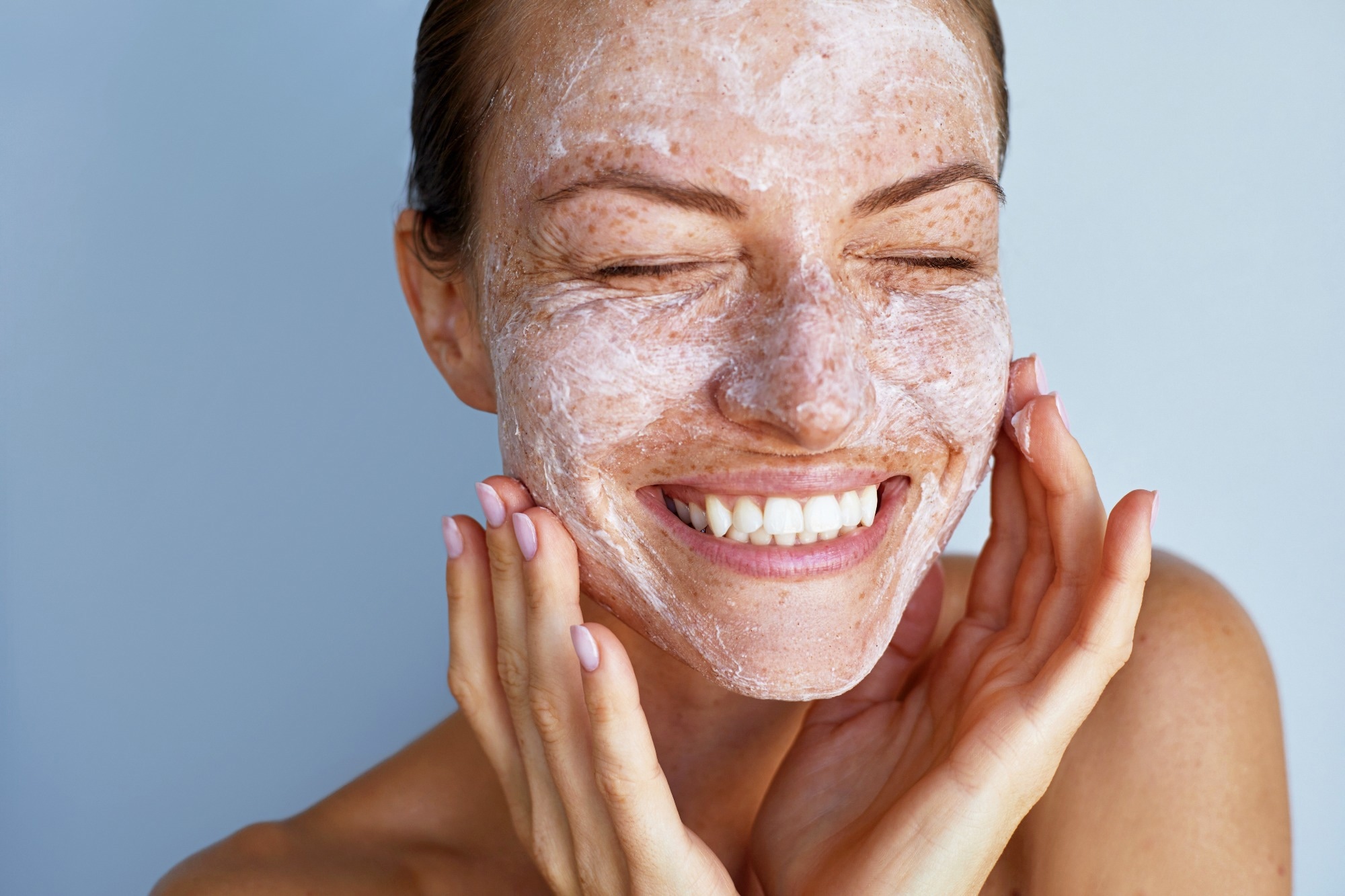 Woman applying white peeling cosmetic product to whole her face