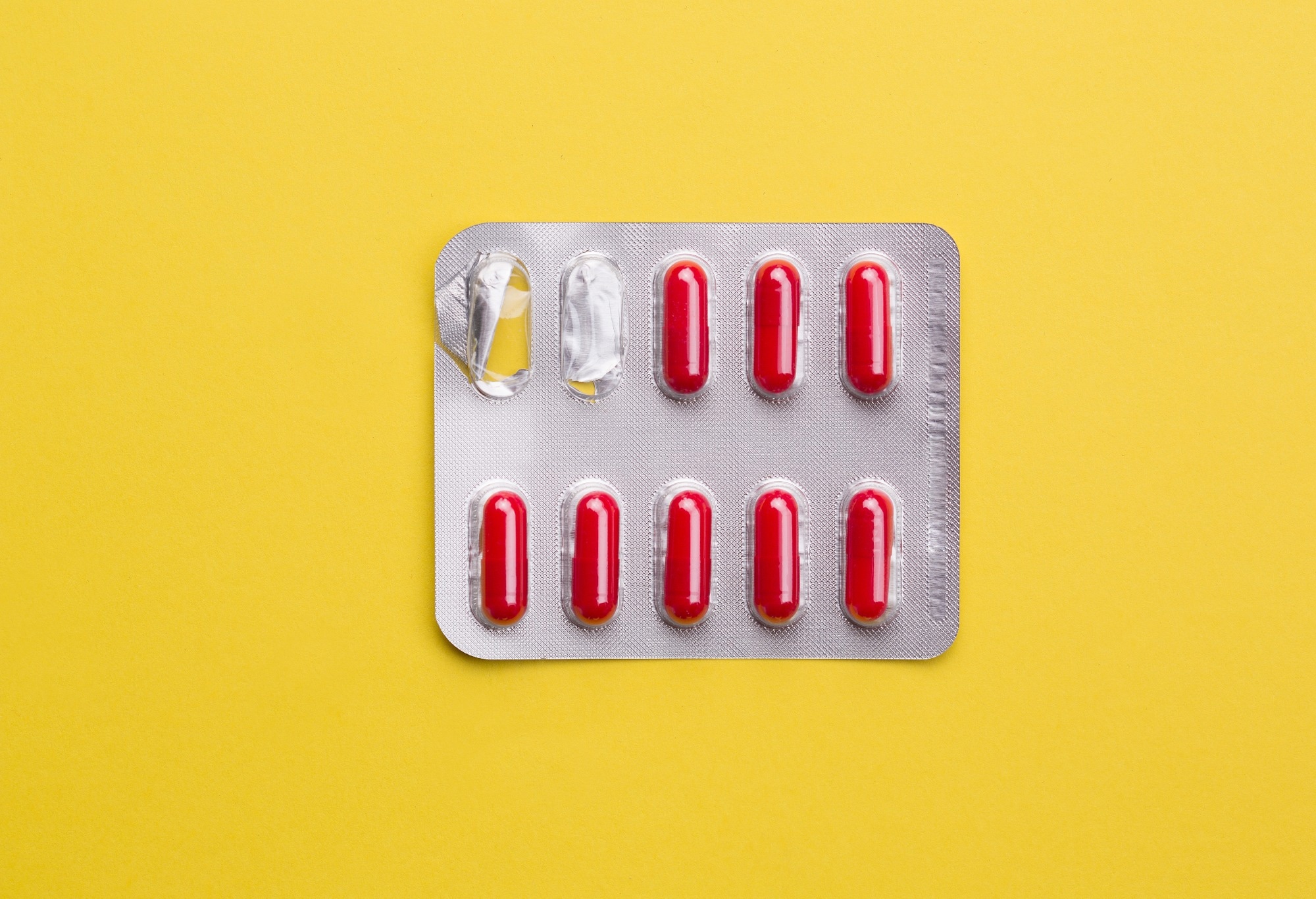 Yellow Background of red pills in silvery blister