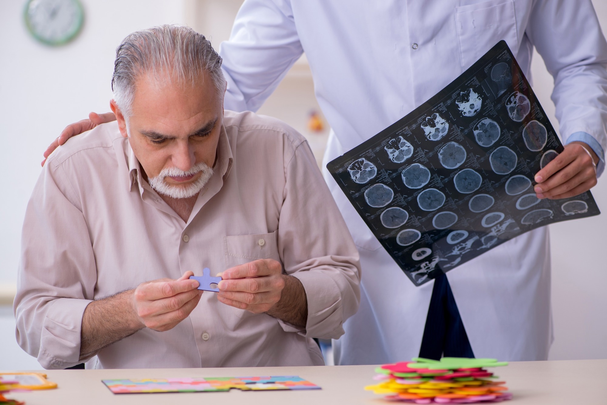 Doctor with brain scans in hand and patient suffering from Alzheimer disease completing a jigsaw