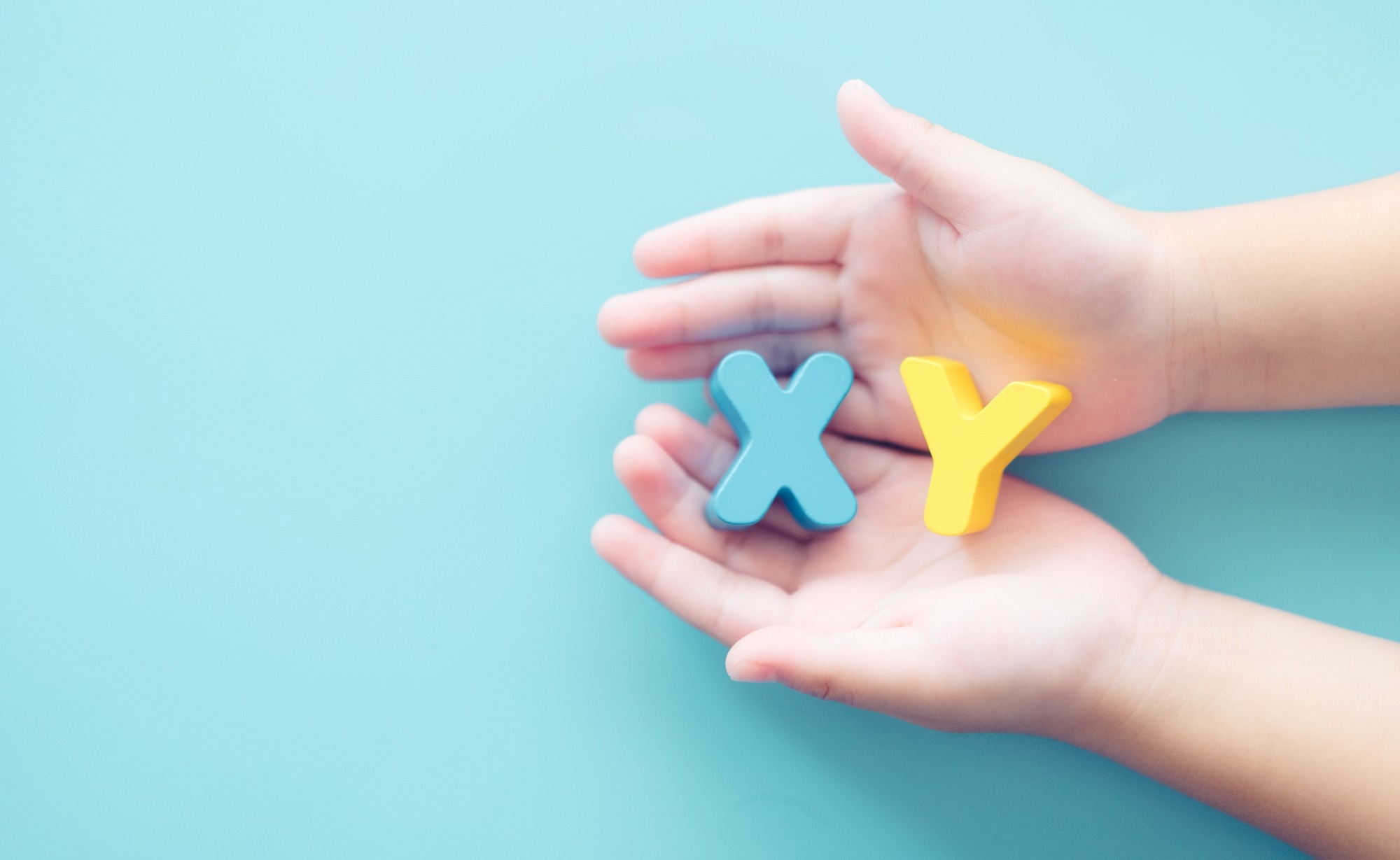 XY chromosome letters on young boy hands. Blue background