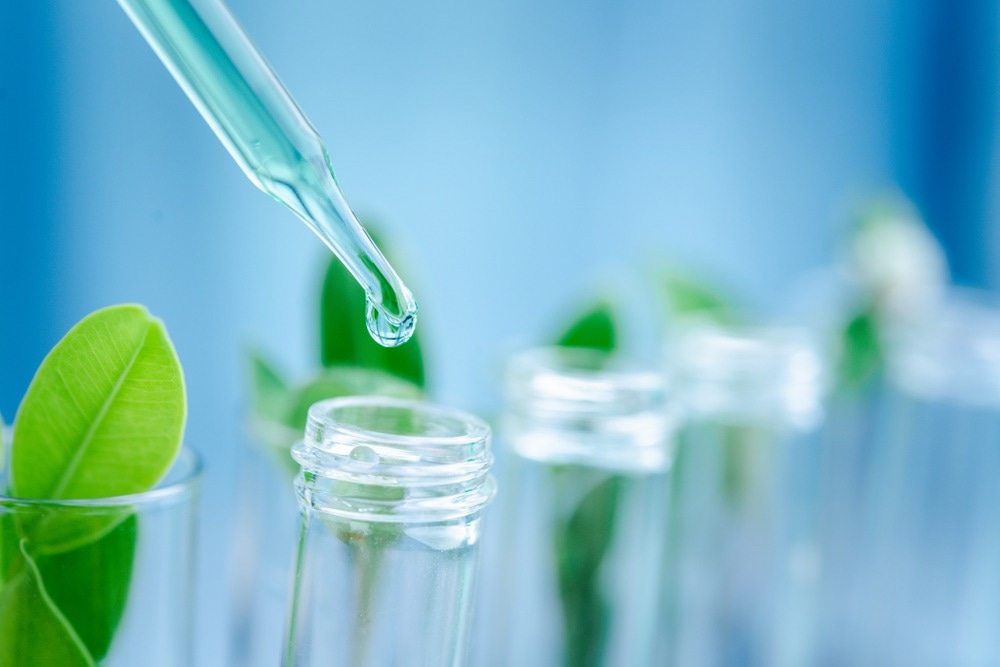 Dropper over test tube dropping sample chemical into sample herbal plaint , biotechnoloy research concept.