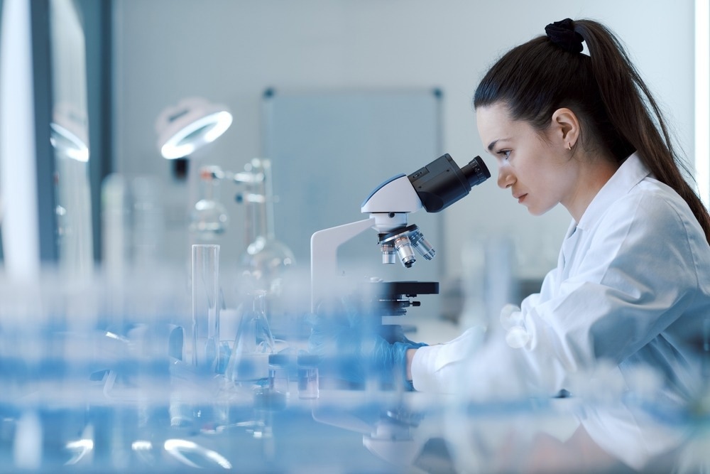 woman looking through microscope