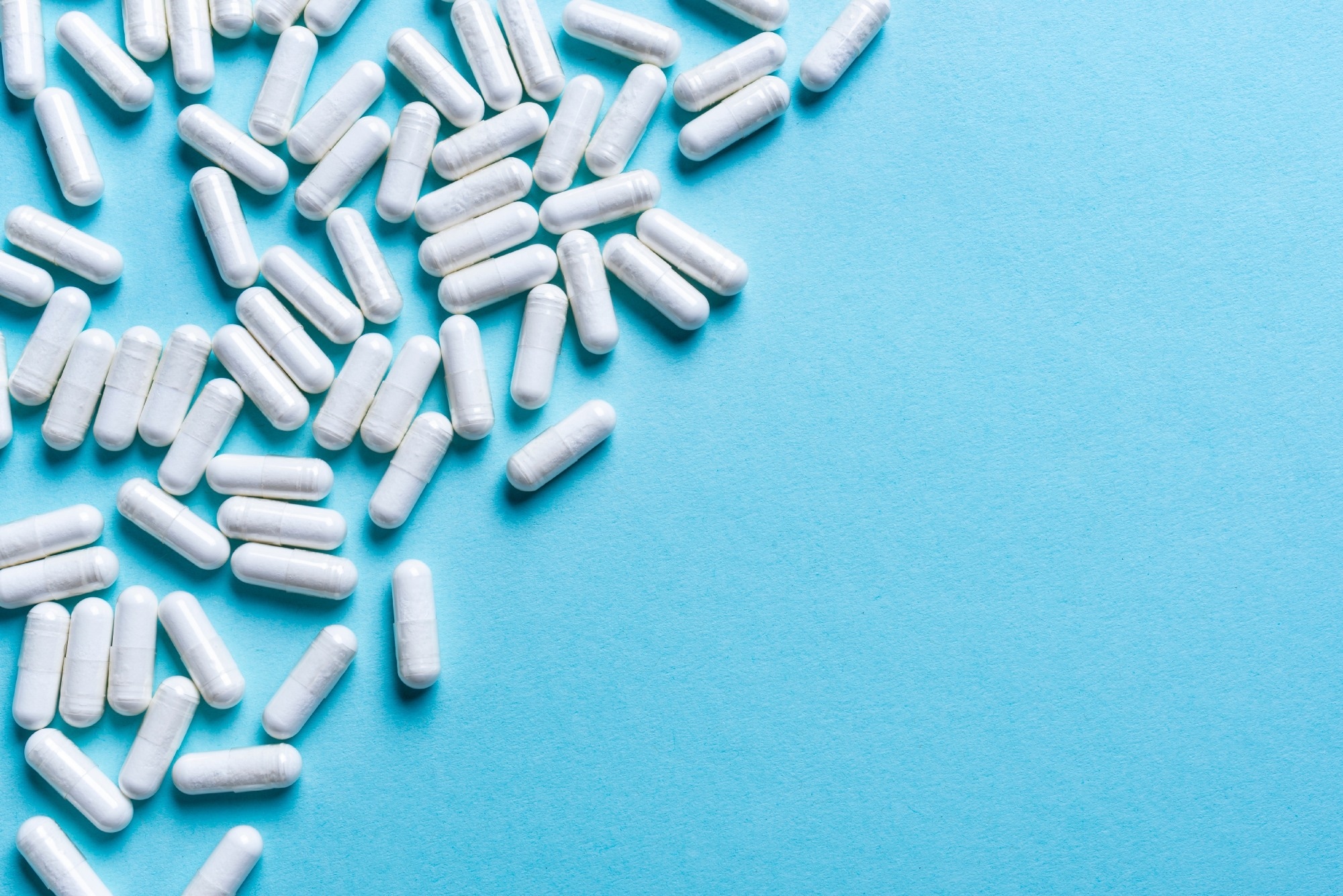 White medical capsules on light blue background.