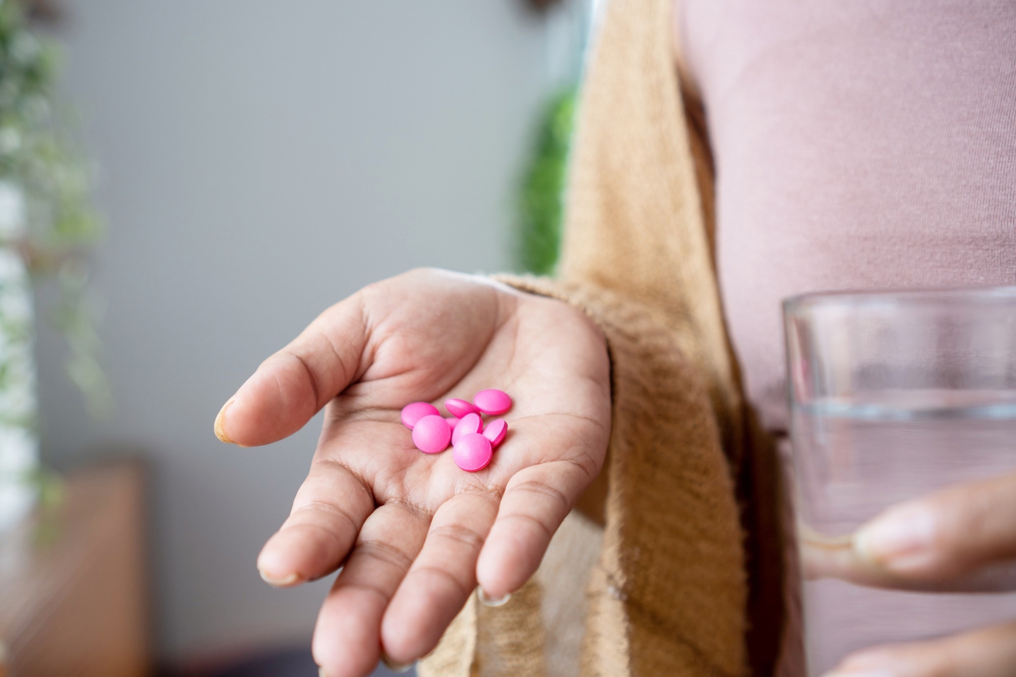 Woman hand taking painkiller pink ibuprofen pills , handful of overdose medicines.
