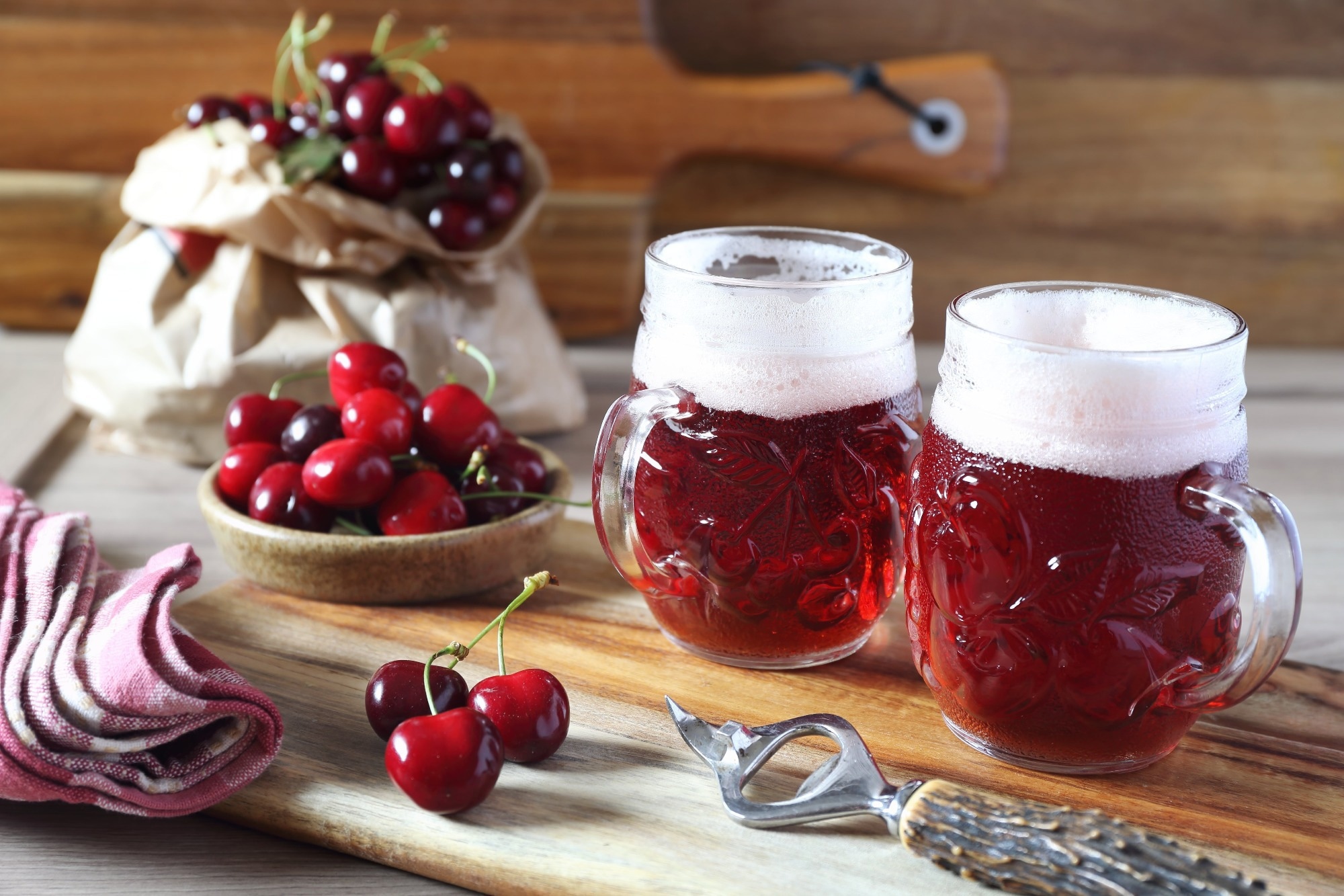 Light fruit craft beer and cherry on wooden chopping board, rustic style.
