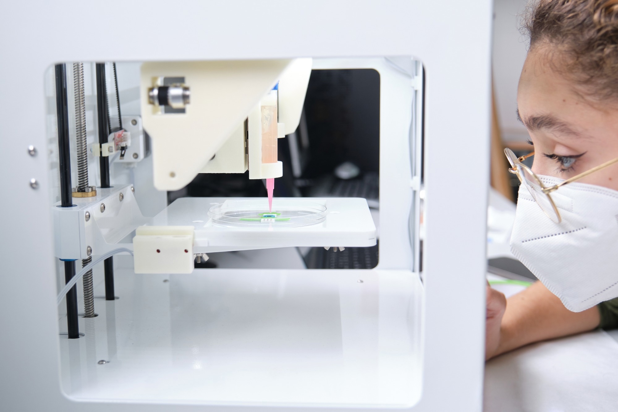 Researcher adjusting a 3D bioprinter to 3D print cells onto an electrode