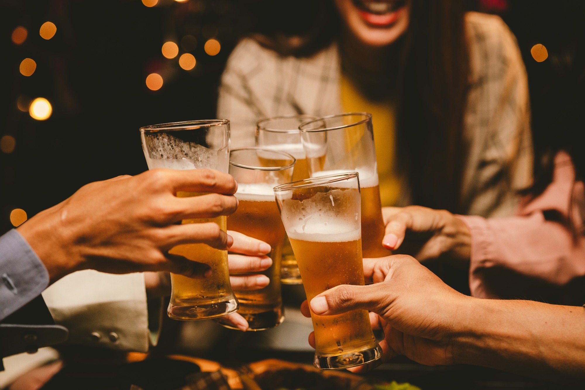 friends celebrates, clinking glasses of beer together in a joyful manner